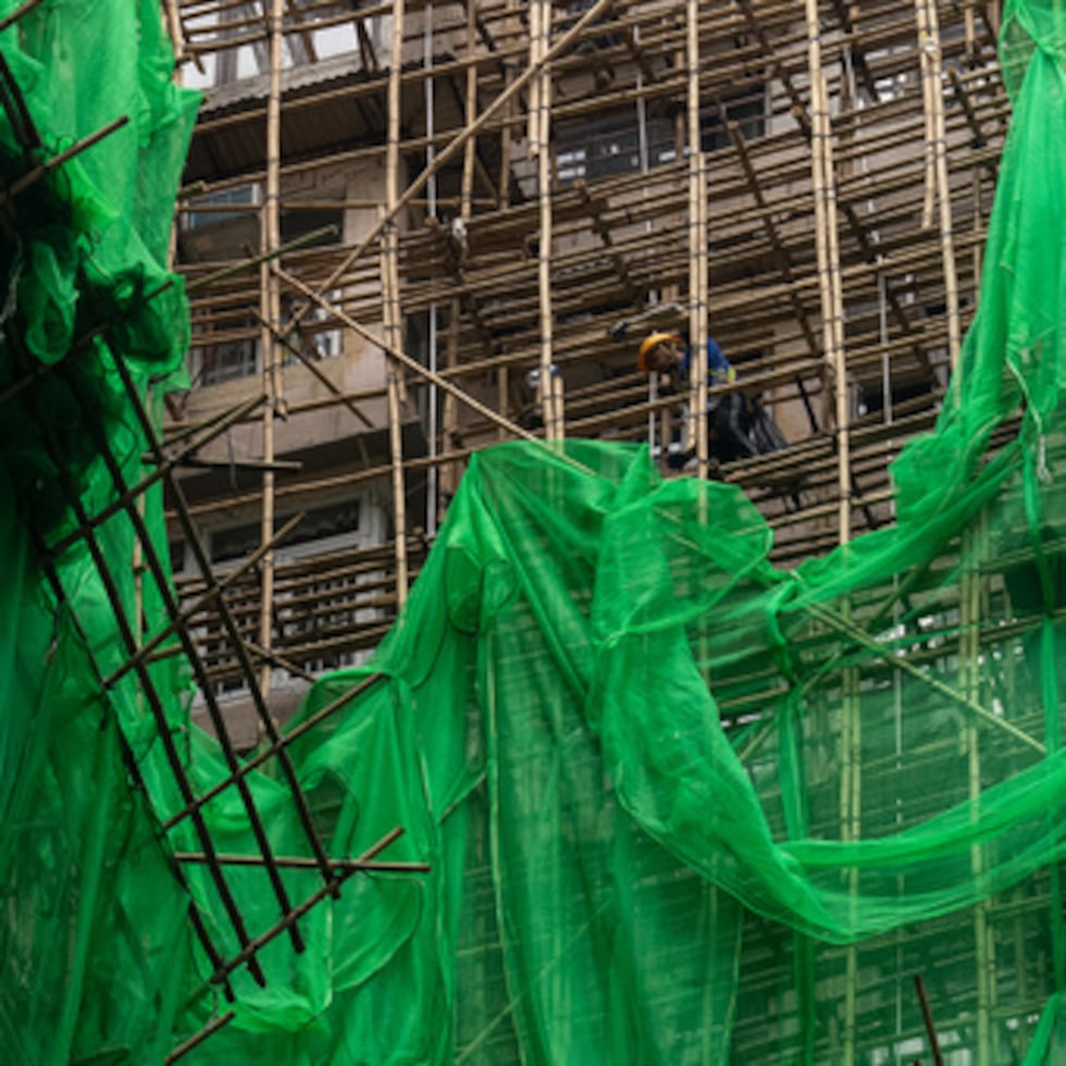Trabajadores de la construcción retiran las redes de los andamios de un proyecto de renovación en el distrito de Quarry Bay tras el incendio mortal en Wang Fuk Court, en el distrito de Tai Po de los Nuevos Territorios de Hong Kong, el jueves 4 de diciembre de 2025. (AP Photo/Chan Long Hei)