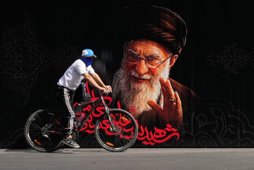 Un hombre pasa en bicicleta junto a un retrato del líder supremo iraní asesinado, el ayatolá Alí Jamenei, antes de las ceremonias fúnebres de varios días, el viernes 3 de julio de 2026, en Teherán, Irán. (AP Foto/Vahid Salemi)