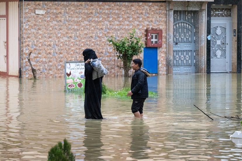 A mother and her son evacuate through a flooded street road after heavy rainfall in Ksar El Kebir, Morocco, Friday, Jan. 30, 2026. (AP Photo)