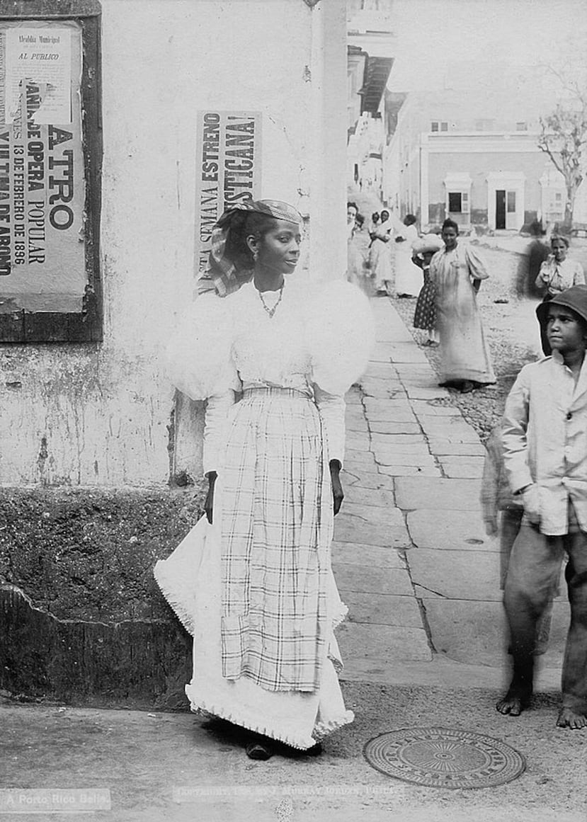 Una fotografía posada de una mulata local. Algunos curiosos la observan al fondo. J. Murray Jordan (1861-1909) fue un fotógrafo y editor estadounidense activo a finales del siglo XIX y principios del XX en Filadelfia.