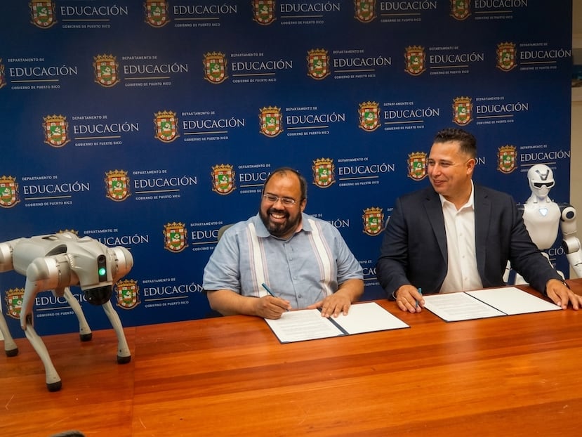 Desde la izquierda: el secretario de Educación, Eliezer Ramos Parés, y el profesor César Cabrera, principal oficial ejecutivo de Techno Inventors, Inc., firman el acuerdo flanqueados por robots.
