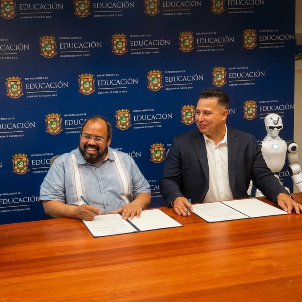Desde la izquierda, el secretario de Educación, Eliezer Ramos Parés, y el profesor César Cabrera, principal oficial ejecutivo de Techno Inventors, Inc., firman el acuerdo flanqueados por robots.