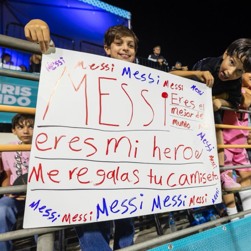 Dos niños sostienen una cartulina con un mensaje a Lionel Messi.