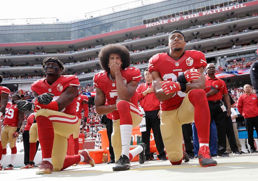 Colin Kaepernick (centro), de los 49ers de San Francisco, se arrodilla con otros compañeros durante la interpretación del himno nacional. (AP)