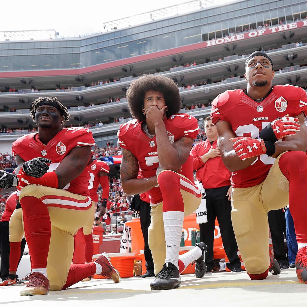 Colin Kaepernick (centro), de los 49ers de San Francisco, arrodillado con otros compañeros durante la interpretación del himno nacional previo a un partido de la NFL.