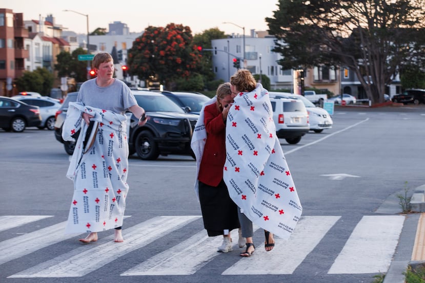 Varias personas se cubren con mantas de la Cruz Roja Americana en Fort Mason, donde la Cruz Roja ha instalado un centro de asistencia para las personas afectadas por un incidente con una embarcación en las aguas cercanas a San Francisco el martes 14 de julio de 2026. (Santiago Mejia/San Francisco Chronicle vía AP)