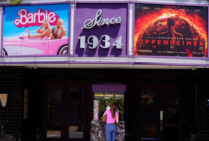 Una persona compra boletos de cine debajo de un cartel con las películas "Barbie" y "Oppenheimer" en el cine Los Feliz, en Los Ángeles.