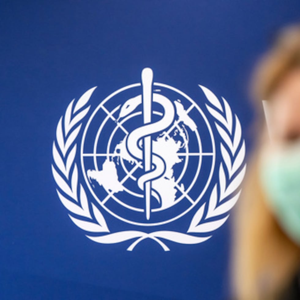 Una persona lleva una mascarilla protectora delante del logotipo de la OMS, durante una rueda de prensa sobre la epidemia de ébola en la sede de la Organización Mundial de la Salud (OMS).