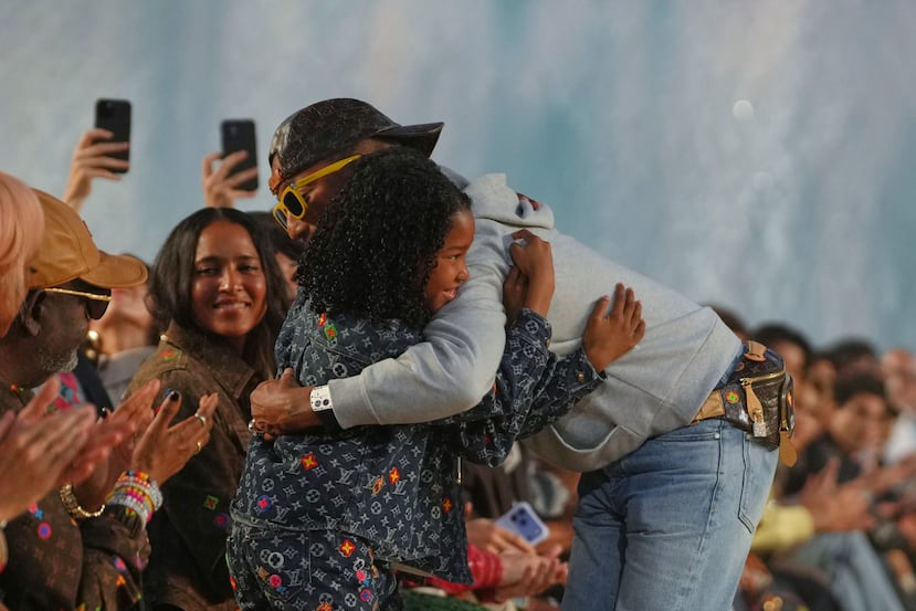 El diseñador Pharrell Williams abraza a su hijo después de prensentar la colección.