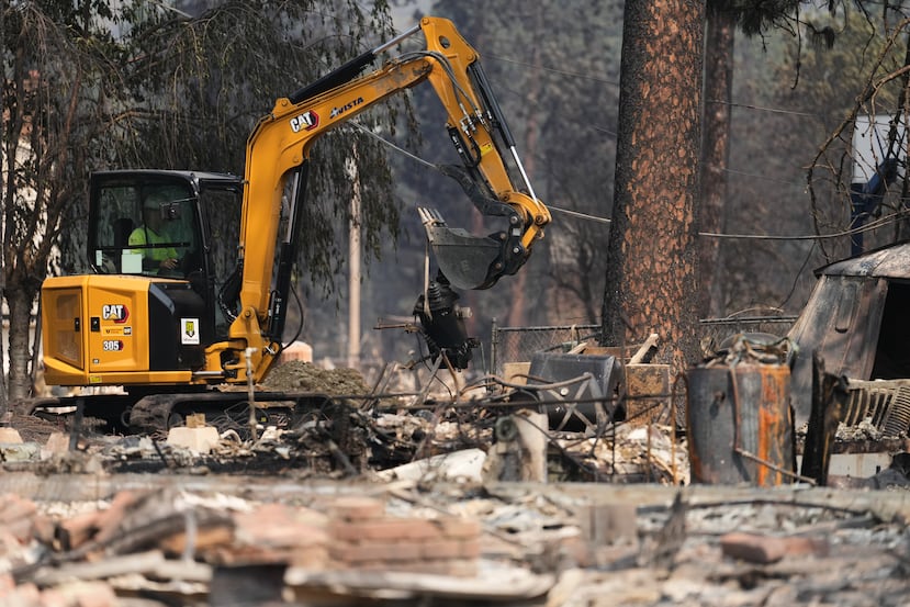 Equipos de bomberos trabajan cerca de varias casas calcinadas tras un incendio forestal que azotó la zona noroeste de Spokane, Washington, el martes 4 de agosto de 2026. (Foto AP/Lindsey Wasson)