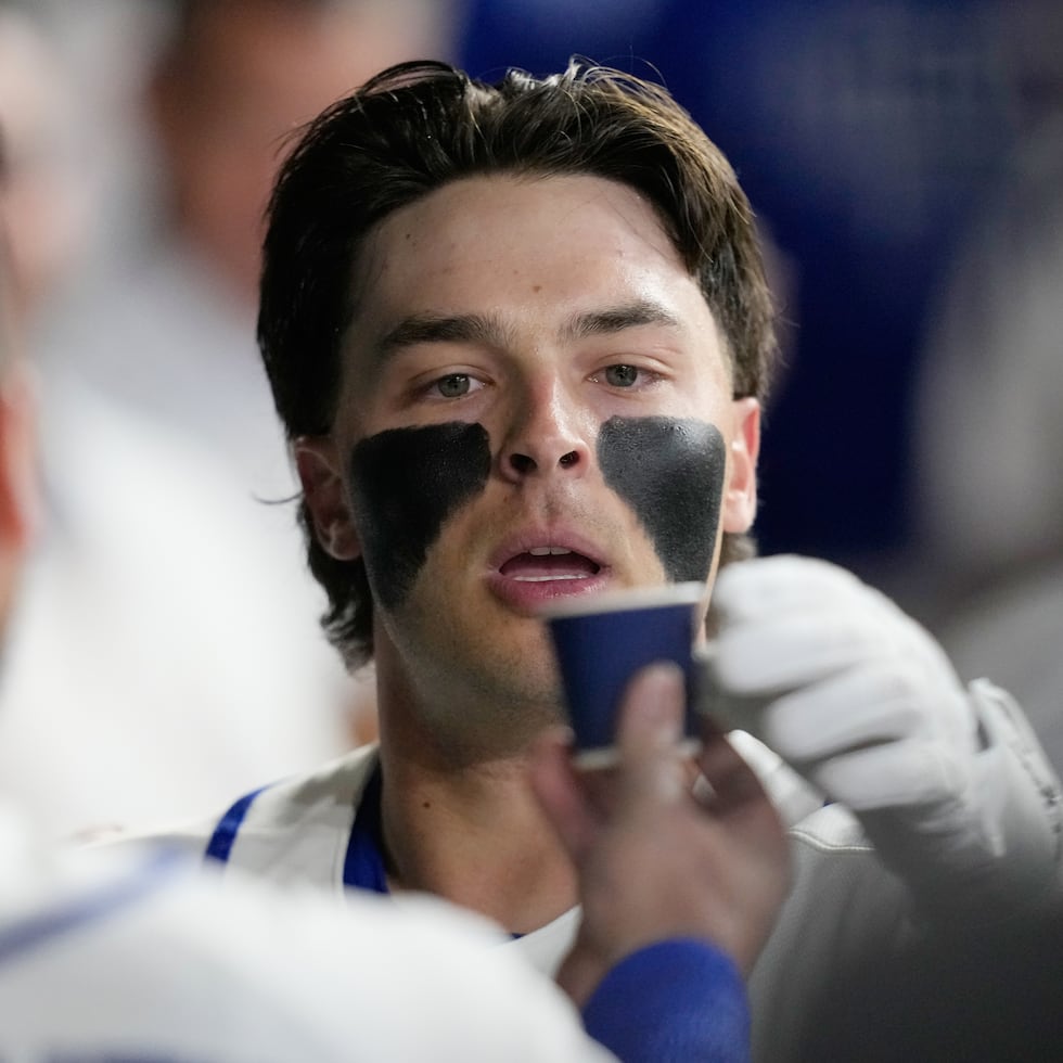 Andrew Fischer recibiendo un vasito con café en el dugout de Italia, luego de conectar un jonrón en el juego contra Gran Bretaña.