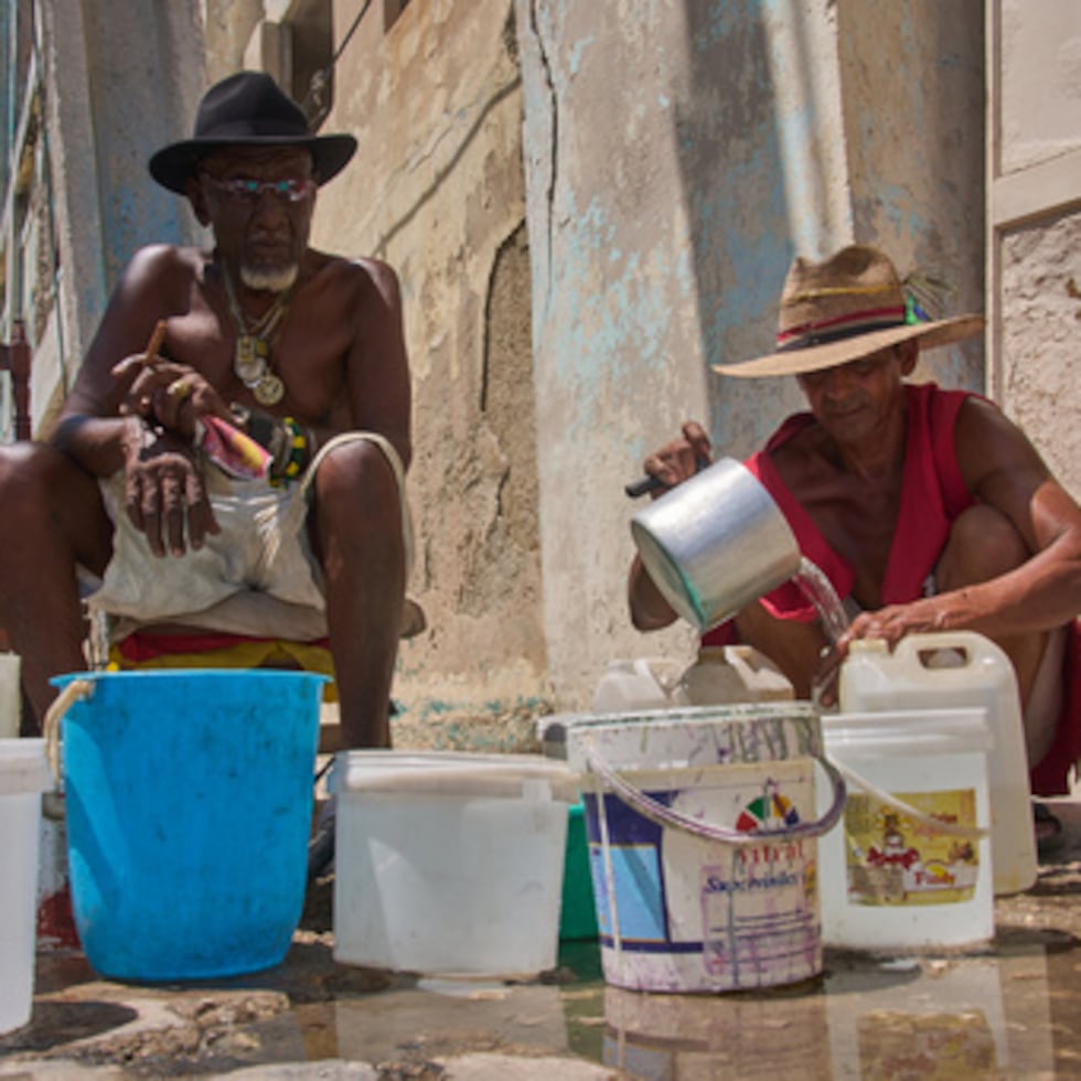 Oscar Joaquín López (izquierda) y Wilfredo Cisneros Duarte recogen agua de una tubería en la calle en La Habana.