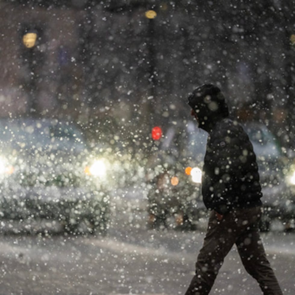 Un hombre cruza la calle 7 en la nieve pesada domingo, 28 de diciembre 2025 en el centro de Minneapolis.