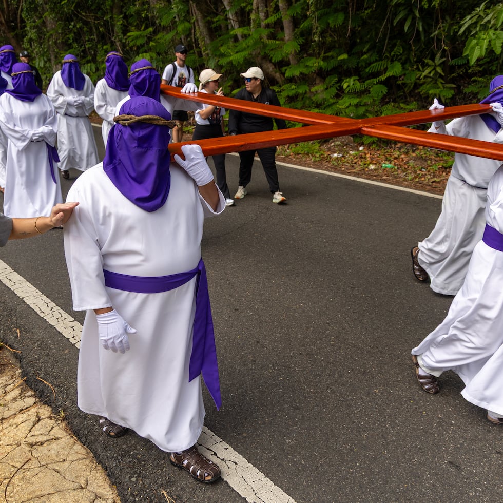 Los nazarenos encapuchados cargan la cruz por un largo tramo como penitencia.