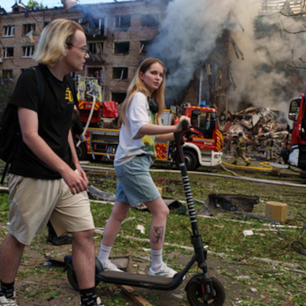 Varias personas pasan junto a un edificio residencial en llamas, destruido por un ataque ruso en el barrio de Lukianivka, en Kiev (Ucrania).