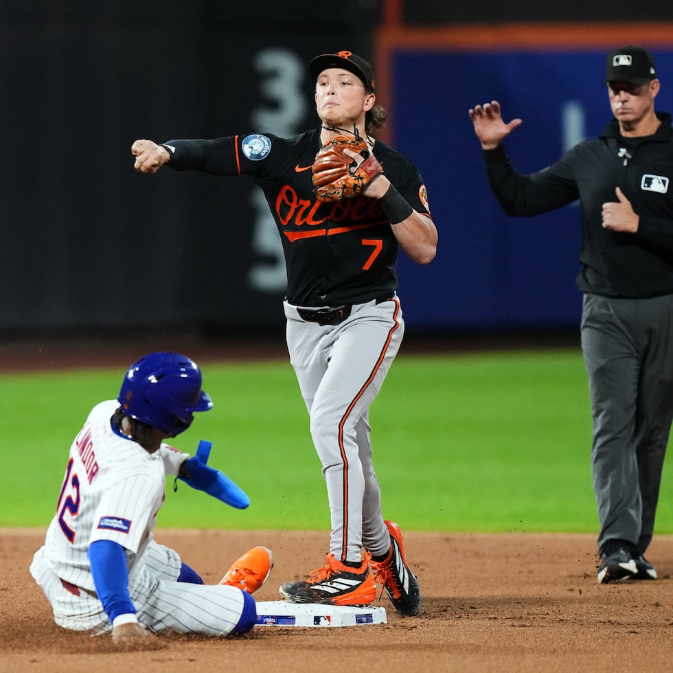 Jackson Holliday, de los Orioles de Baltimore, da el out en segunda base al boricua Francisco Lindor, de los Mets, y tira a primera para completar una doble jugada.