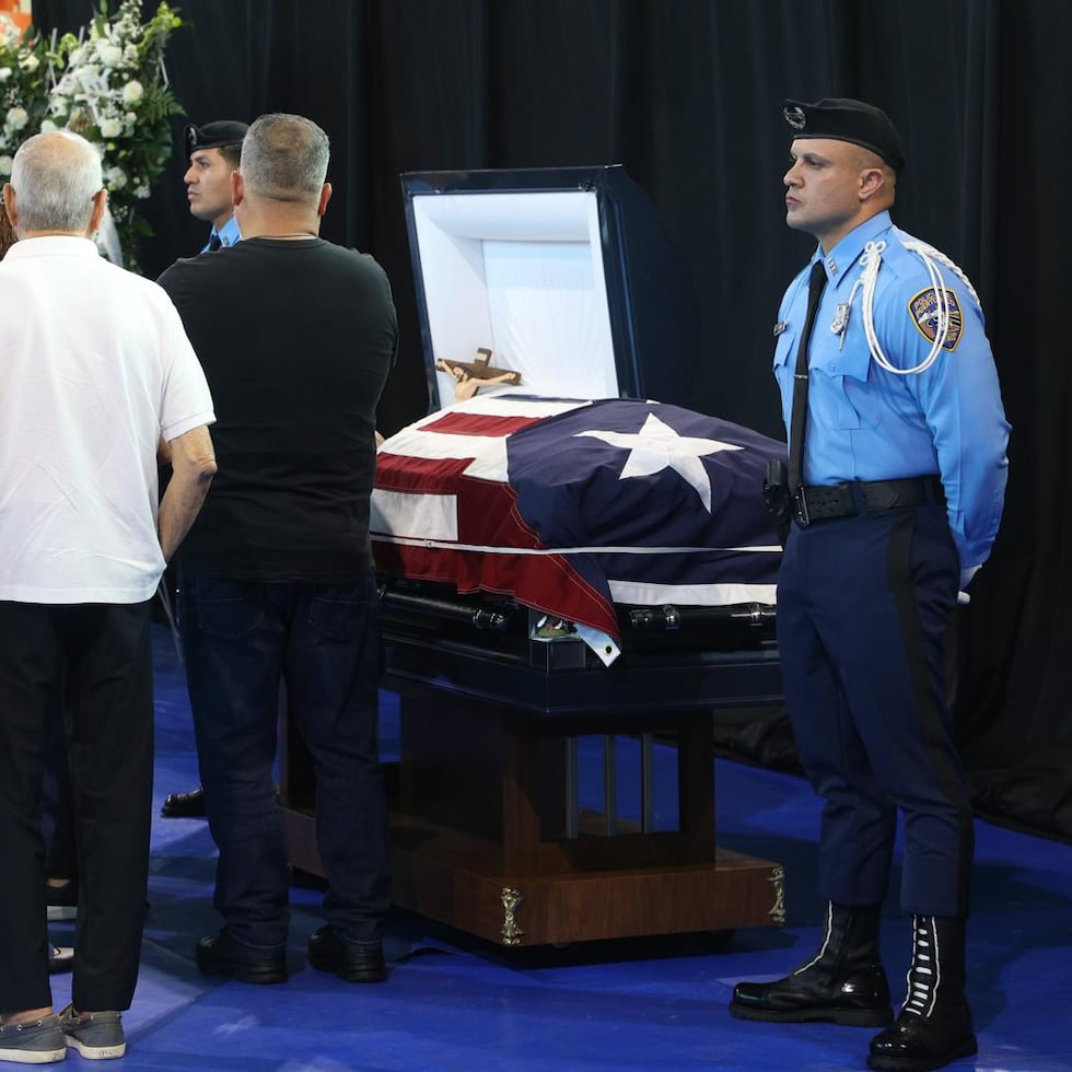 Un agente de la Policía realiza una guardia de honor junto al férretro del agente Eddie Santiago Renta.