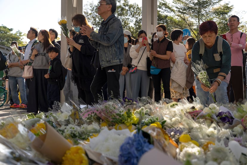 Gente acude a dejar flores cerca de donde días atrás ocurrió un fatal incendio en un complejo de torres de departamentos en Tai Po, Hong Kong, el 29 de noviembre de 2025. (Foto AP/Ng Han Guan)