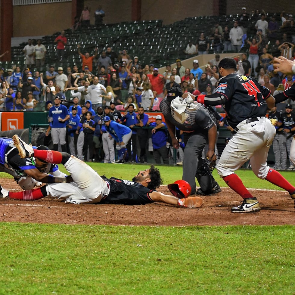 M.J. Meléndez, de los Criollos, es sacado fuera en el plato por Brian Navarreto en intento de anotar en la duodécima entrada del sexto juego de semifinal.