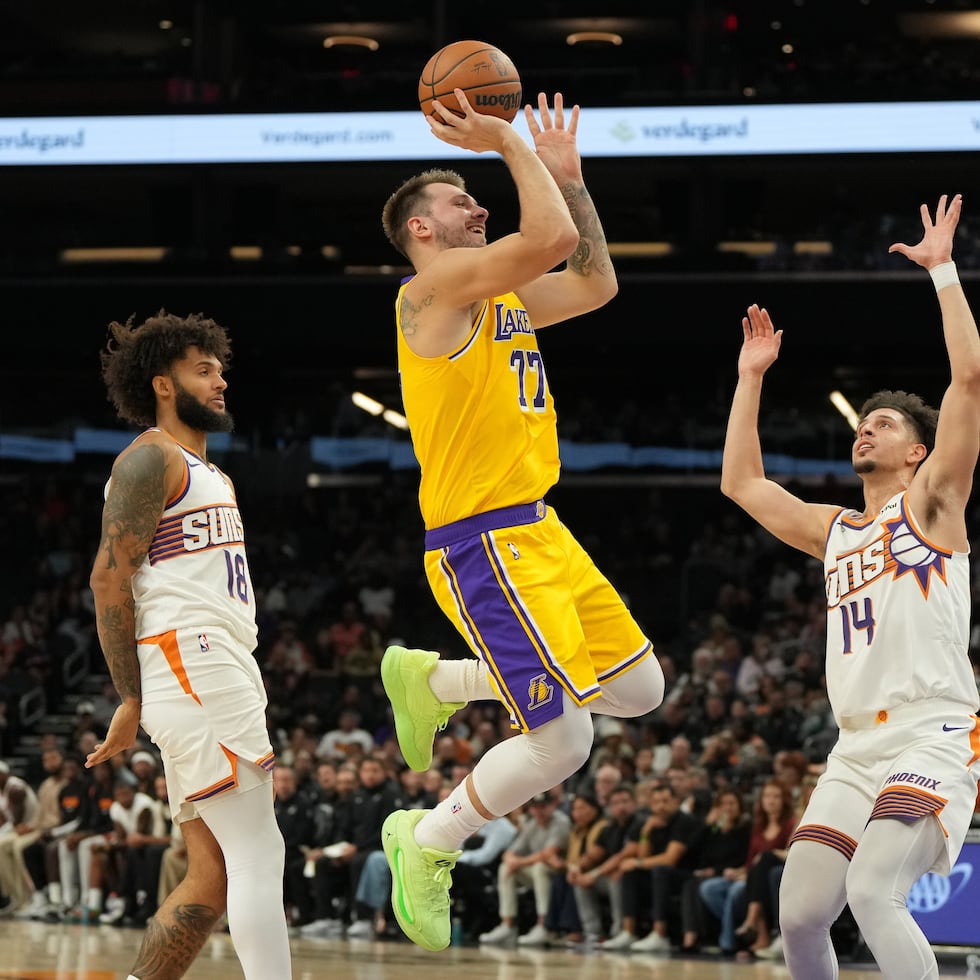 El alero de los Lakers de Los Ángeles Luka Dončić lanza el balón sobre Isaiah Livers y Joby Brea, de los Suns de Phoenix, en el encuentro de pretemporada del martes 14 de octubre del 2025.