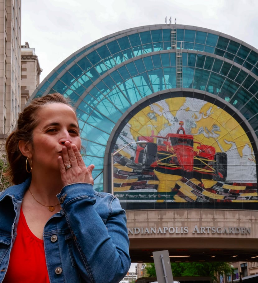 La puertorriqueña Frances Ruiz posa frente a una imagen de su obra "Racing History of the World”, que servirá para dar la bienvenida a todos aquellos que visiten la ciudad de Indianápolis durante las semanas previas a la carrera Indy 500.