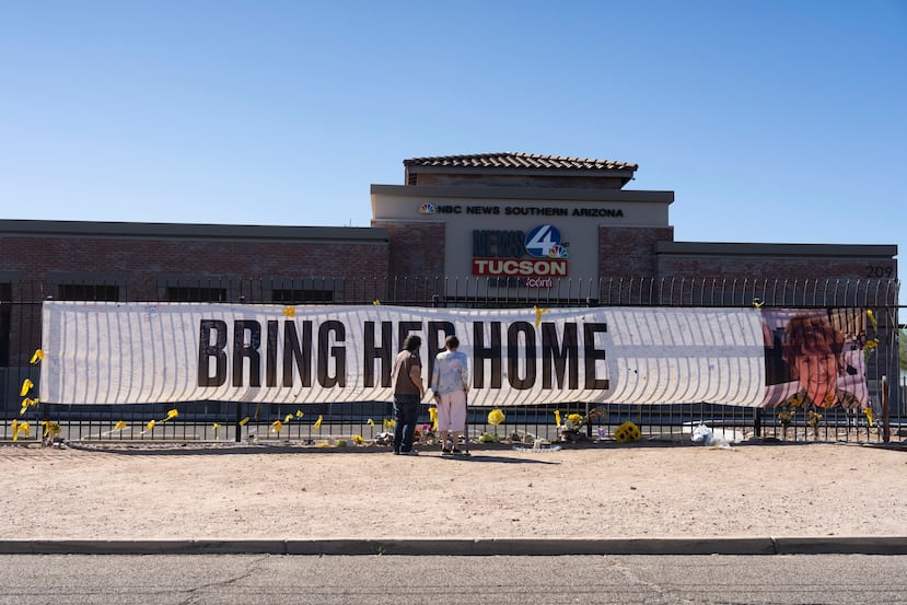 ARCHIVO - Varias personas visitan una pancarta en memoria de Nancy Guthrie, la madre desaparecida de Savannah Guthrie, presentadora del programa "Today", frente a la sala de redacción de KVOA en Tucson, Arizona, el 6 de marzo de 2026. (Foto AP/Rebecca Noble, Archivo)