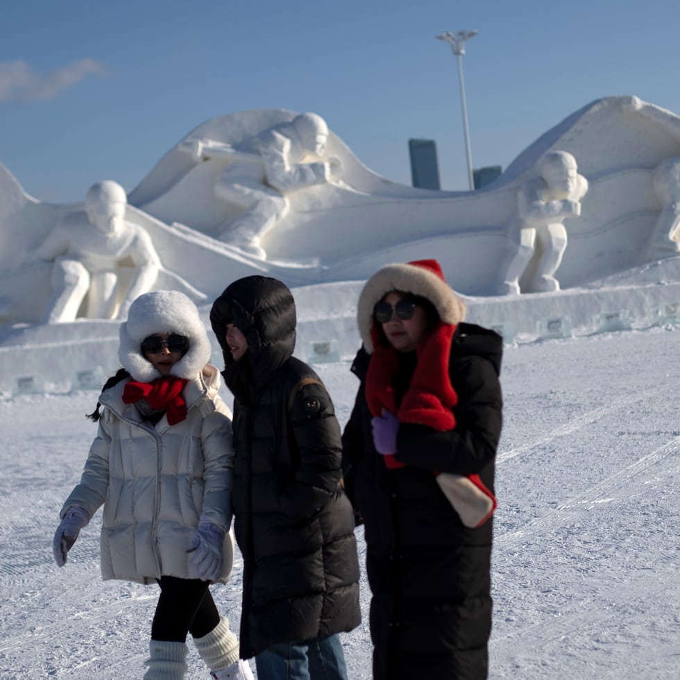 Personas caminan cerca de esculturas de hielo en un festival en Harbin, en la provincia china de Heilongjian.
