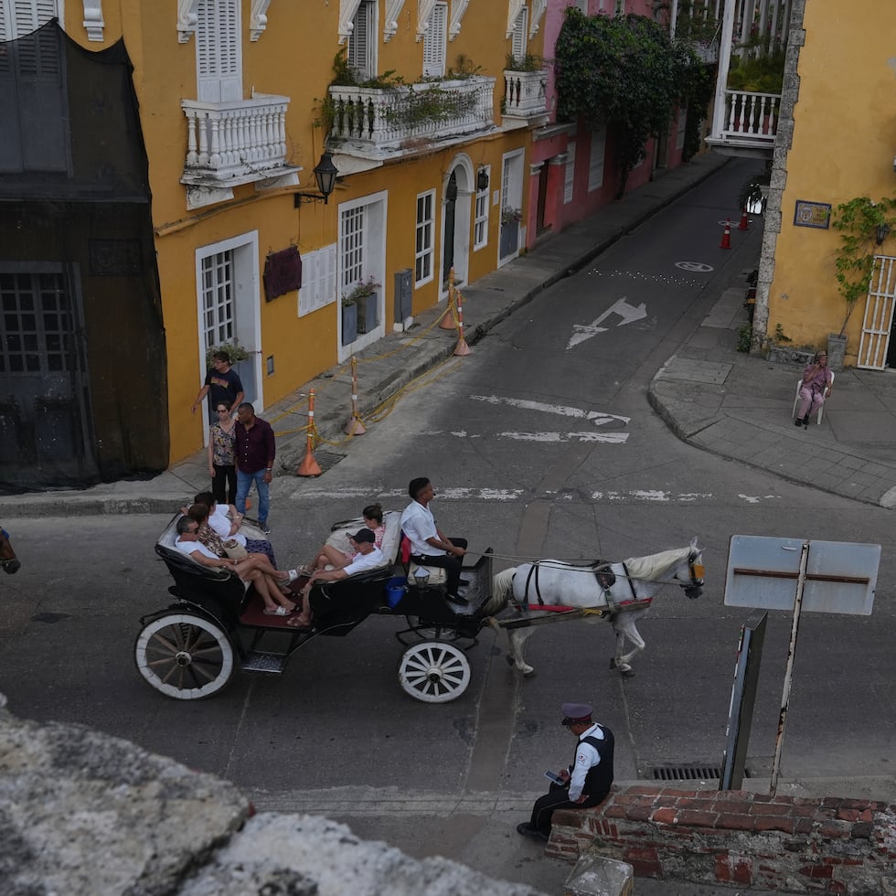 Turistas circulan en un coche de caballos tradicional por el centro de la ciudad de Cartagena, Colombia.