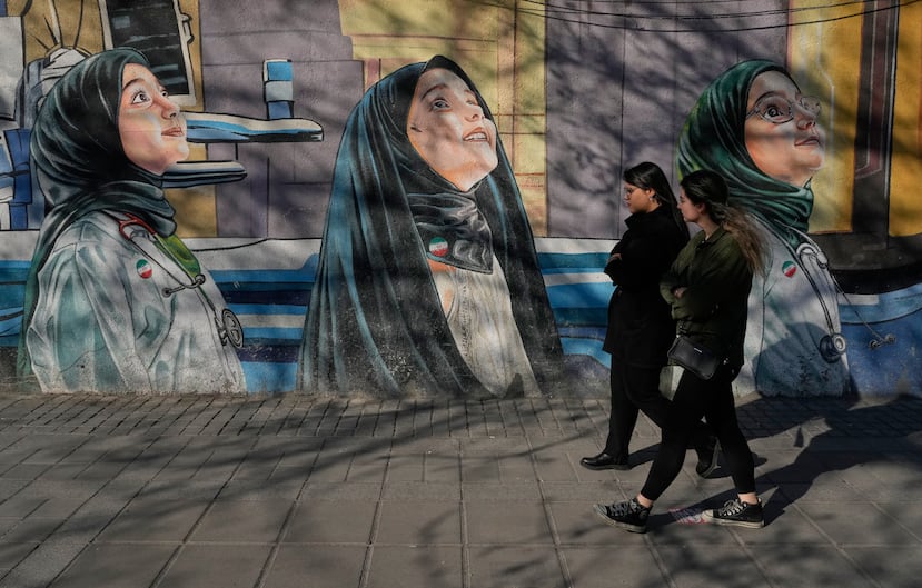 Women walk past a mural at a girls school at Enqelab-e-Eslami, or Islamic Revolution Street in downtown Tehran, Iran, Wednesday, Feb. 25, 2026. (AP Photo/Vahid Salemi)