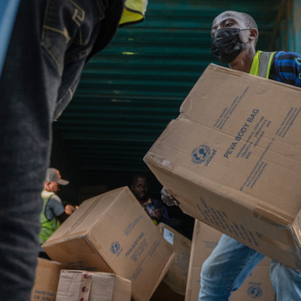Varias personas descargan un cargamento de más de 15 toneladas de suministros donados por UNICEF.