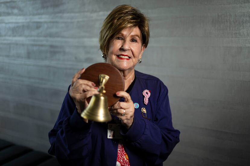 La voluntaria y también sobreviviente de cáncer, Marian Diez sostiene la primera campana que llevó ella misma al Centro de Cáncer, que luego reemplazó por otra más grande.