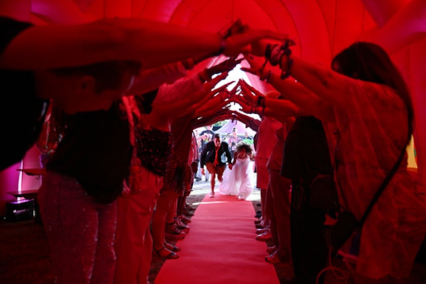 Los invitados forman un arco humano para una pareja mientras esta entra en una capilla hinchable durante una boda colectiva celebrada en Ámsterdam, Países Bajos.