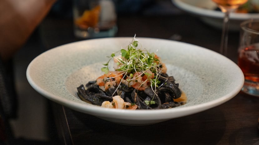 Fettuccine con tinta de calamar, tomates asados, camarones y albahaca, sobre un guiso de limón, mantequilla y vino blanco de Prole Cocina & Barra.