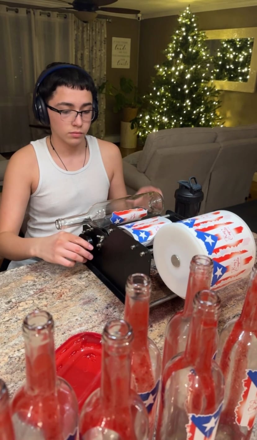 Hijo de Kayla Lalles Silva prepara las etiquetas de las botellas.