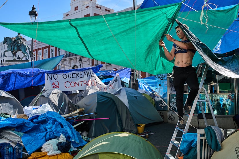 Un hombre instala una cubierta en una tienda de campaña en el campamento improvisado por manifestantes que exigen leyes más estrictas para proteger a los inquilinos, en la plaza Puerta del Sol, en Madrid, España.