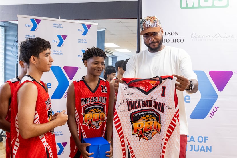 Carmelo Anthony recibe de obsequiso y agradecimento una camiseta de baloncesto de la YMCA por jugadores del programa de básket de la institución cristiana.