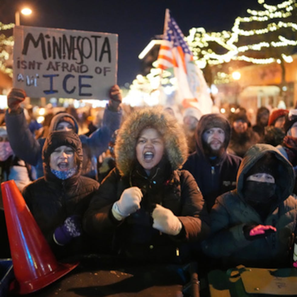 Manifestantes corean y golpean cubos de basura mientras permanecen detrás de una barricada improvisada durante una protesta en respuesta a la muerte de Alex Pretti, de 37 años, que fue abatido mortalmente por un agente de la Patrulla Fronteriza de EE.UU. a primera hora del día, el sábado 24 de enero de 2026, en Minneapolis. (AP Photo/Adam Gray)