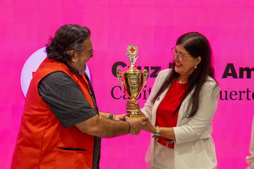 Alberto Fernandini, oficial regional de Filantropía de la Cruz Roja Americana Capítulo de Puerto Rico, le entrega la Copa de la Cruz Roja a Rosalyn M. Toledo, consejera del Consejo Juvenil de The Baldwin School of Puerto Rico.