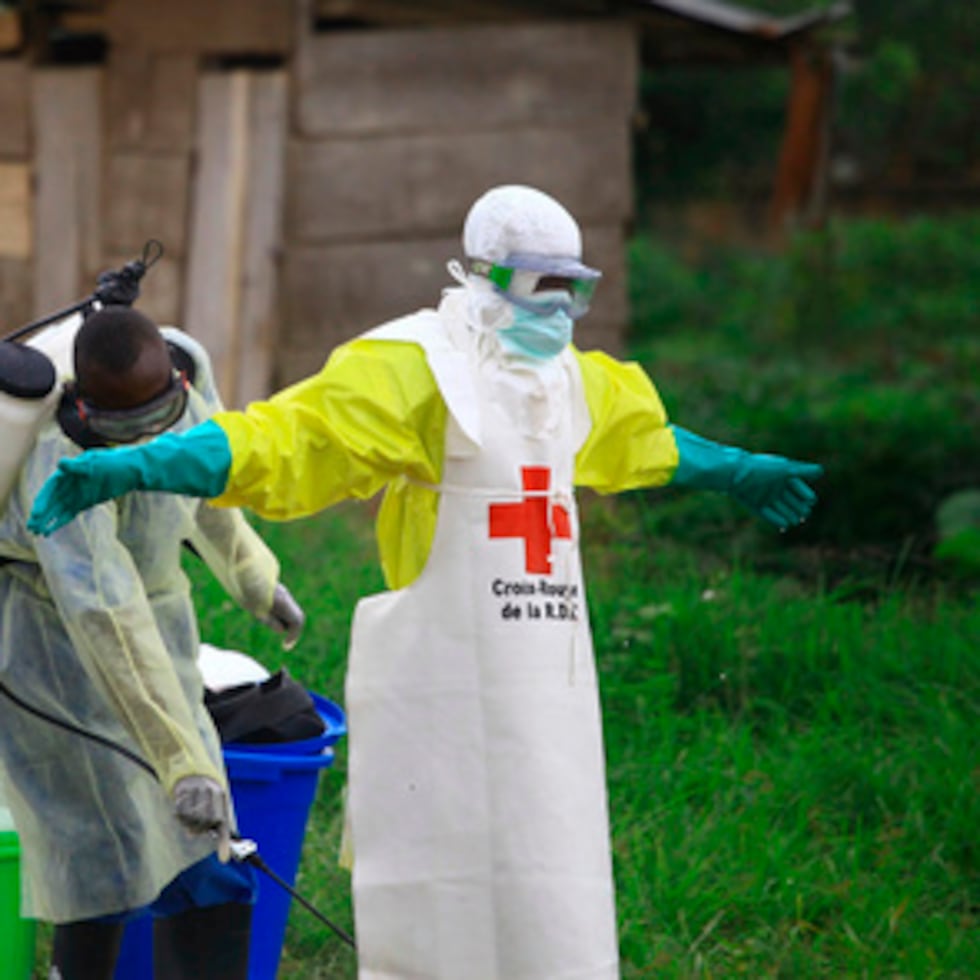 En una foto de archivo de 2018, un trabajador sanitario rocía desinfectante a su colega después de trabajar en un centro de tratamiento del ébola en Beni, al este del Congo.