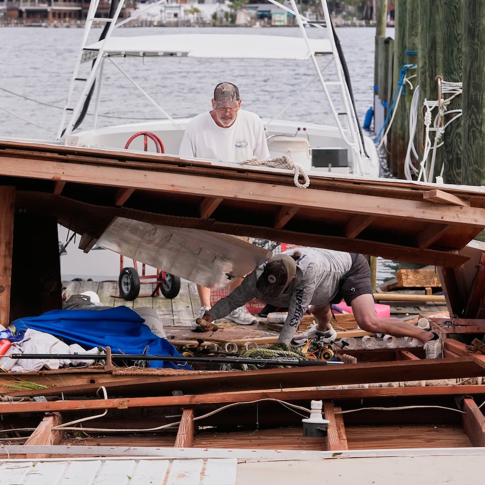 Personas recuperan sus pertenencias de una casa para botes colapsada tras el paso del huracán Isaías en Destin, Florida.