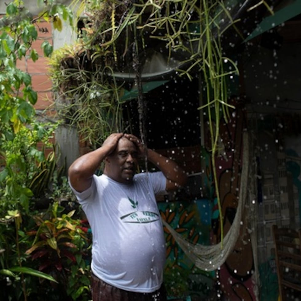 Luis Cassiano se refresca con agua de su techo verde en Río de Janeiro.