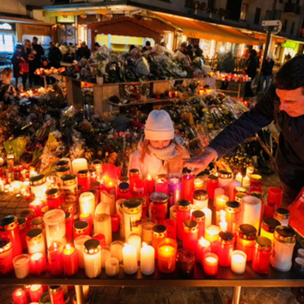 ARCHIVO - Un niño observa mientras un adulto coloca una vela fuera del bar sellado Le Constellation en Crans-Montana, Alpes suizos, Suiza, sábado 3 de enero de 2026, donde un devastador incendio dejó muertos y heridos durante las celebraciones de Año Nuevo. (AP Photo/Baz Ratner, Archivo)
