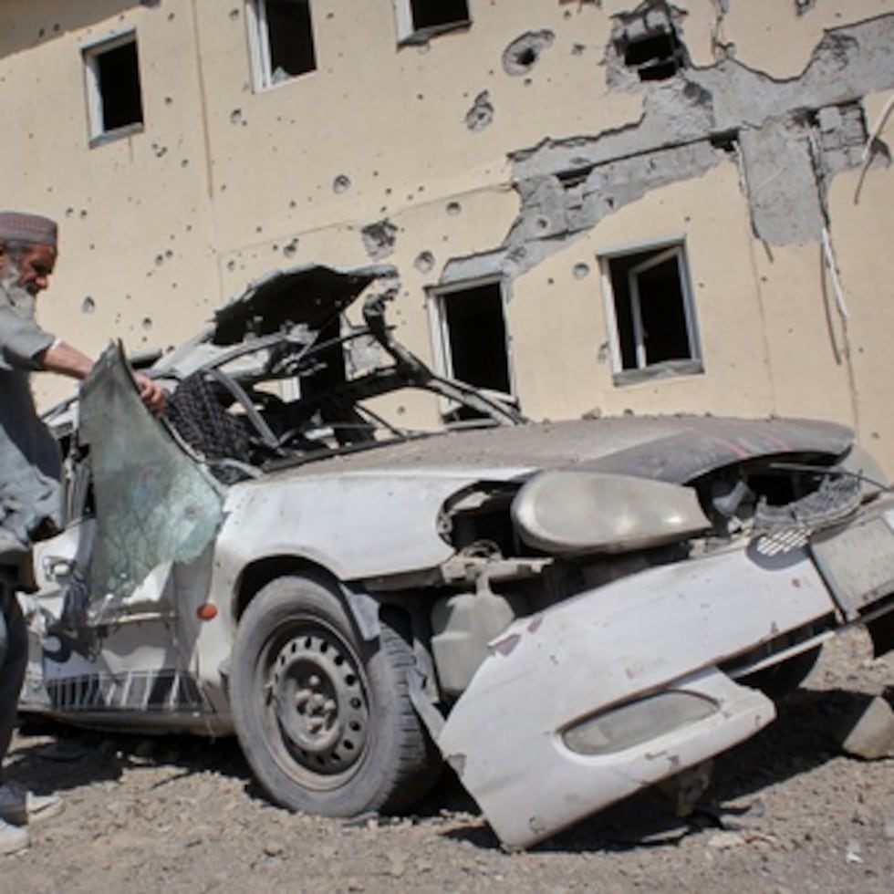 Un hombre inspecciona un coche dañado tras un ataque pakistaní.
