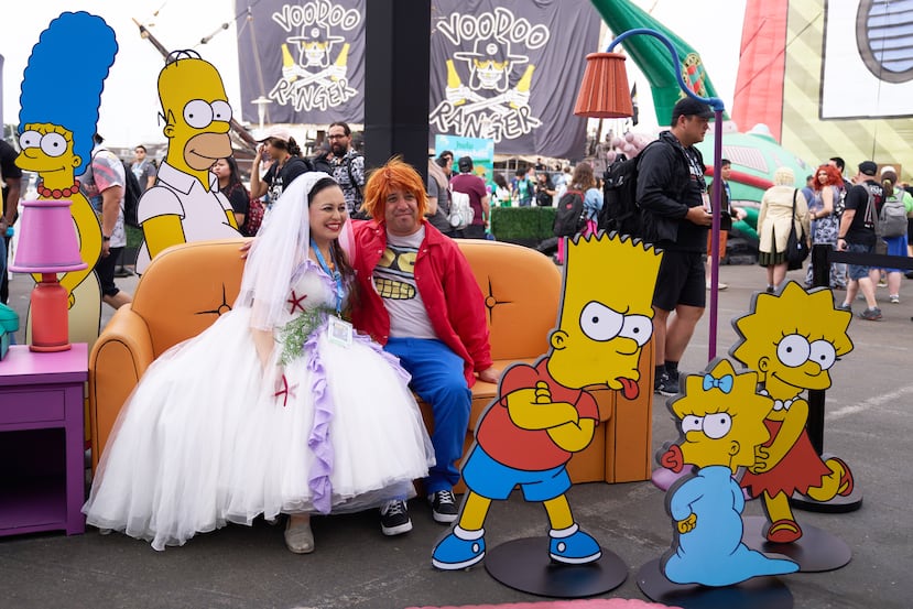 Dos personas posan frente a los personajes del programa "The Simpsons" a las afueras del Comic-Con 2023, celebrado en San Diego, California.
