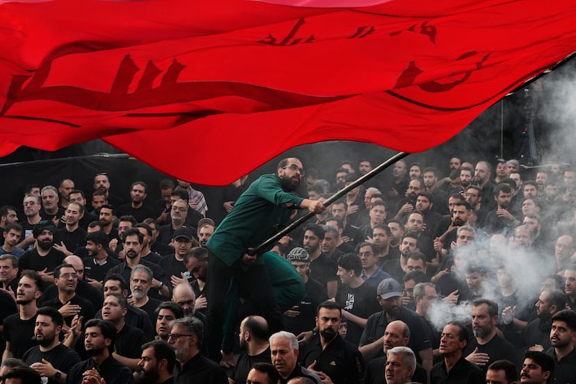 Un hombre ondea una bandera religiosa mientras un grupo de hombres se golpean el pecho durante una ceremonia de duelo en Teherán, Irán, el jueves 18 de junio de 2026, antes del Ashura, la festividad que conmemora el martirio en el siglo VII del nieto del profeta Mahoma, Husayn, quien murió en la batalla de Karbala, en el actual Irak. (AP Foto/Vahid Salemi)