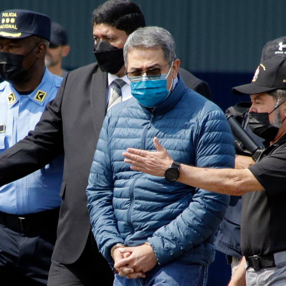 El expresidente hondureño Juan Orlando Hernández, segundo de la derecha, es conducido esposado a un avión que lo espera para su extradición a Estados Unidos, en una base aérea de Tegucigalpa, Honduras, el 21 de abril de 2022.