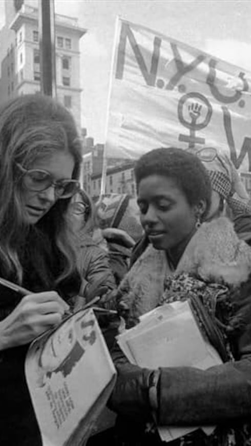 Steinem firma una edición de "El Tacón de la Chancleta", una publicación feminista. A su lado, la licenciada puertorriqueña Ana Irma Rivera Lassén durante una manifestación en Nueva York.