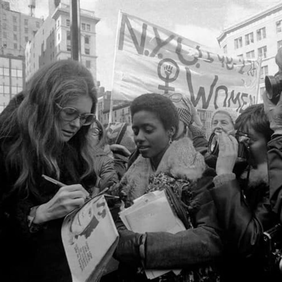 La activista feminista Gloria Steinem firma una edición de "El Tacón de la Chancleta", una publicación feminista que creó MIA y para la que la feminista estadounidense había donado. A su lado, la licenciada Ana Irma Rivera Lassén durante una manifestación en Nueva York.