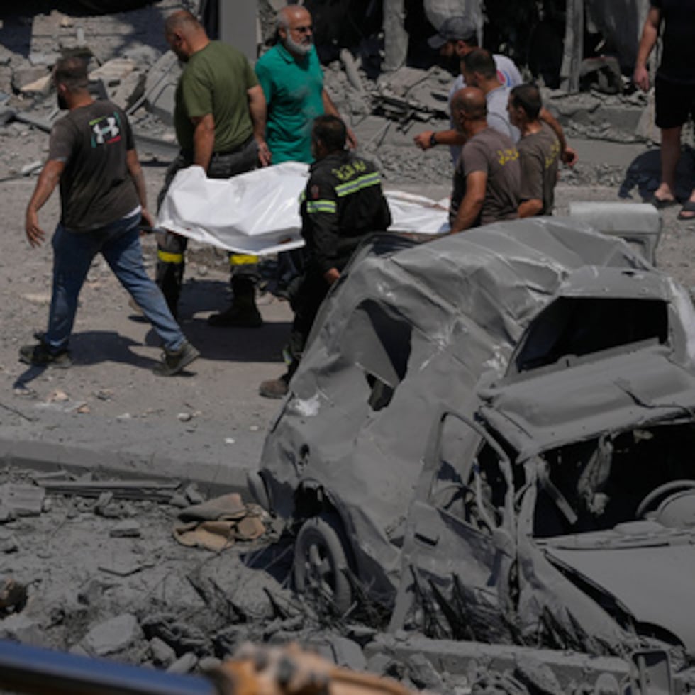 Los equipos de rescate transportan una bolsa de plástico que contiene el cadáver de una persona que perdió la vida en una vivienda alcanzada por un ataque aéreo israelí en la localidad de Deir al-Zahrani, en el sur del Líbano, el sábado 15 de agosto.