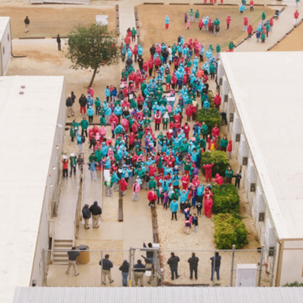 Personas detenidas en el Centro Residencial Familiar del Sur de Texas agitan carteles durante una protesta en Dilley, Texas.